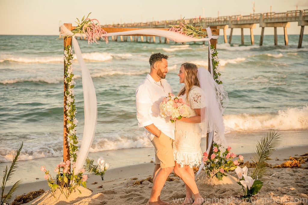 Miami Beach Photography 5 Bride and groom embracing at sunset on a Miami beach during their intimate wedding, with golden light and calm ocean waves as the backdrop.