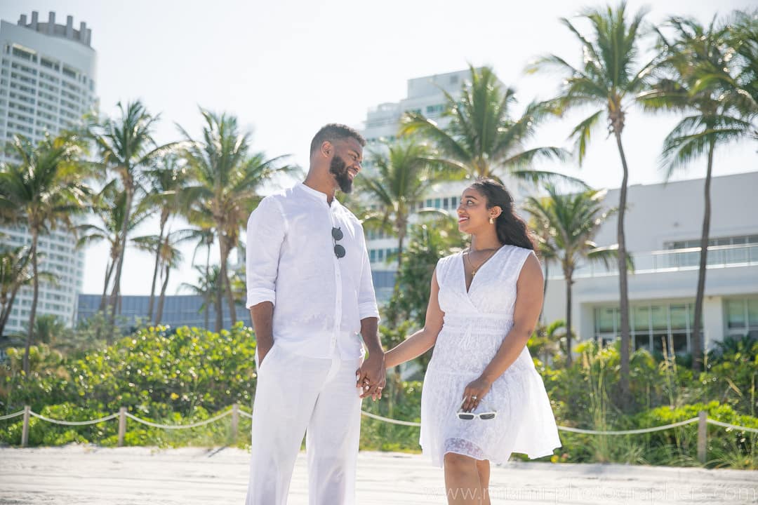 Couple sharing a romantic embrace during a Miami beach photoshoot at sunset with soft golden light.