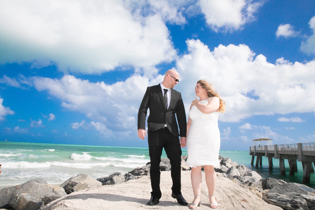 Newlywed couple holding hands and smiling outside Miami Beach City Hall after their wedding ceremony