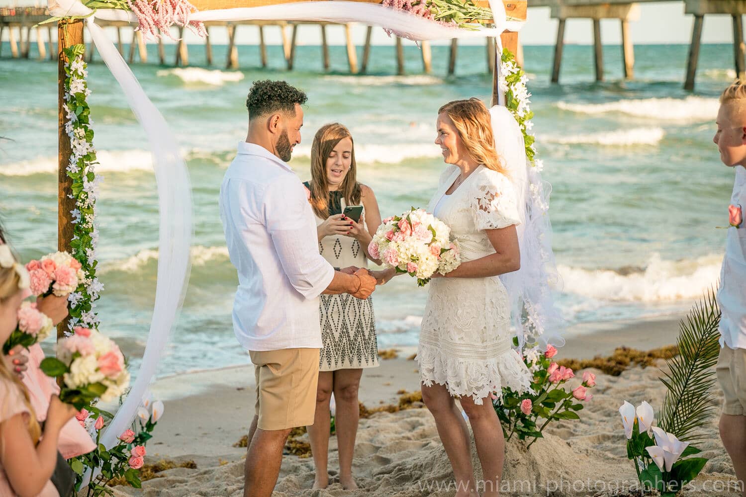 Bride and groom sharing an intimate embrace on the sandy shore during their Miami Beach wedding, captured by a professional photographer