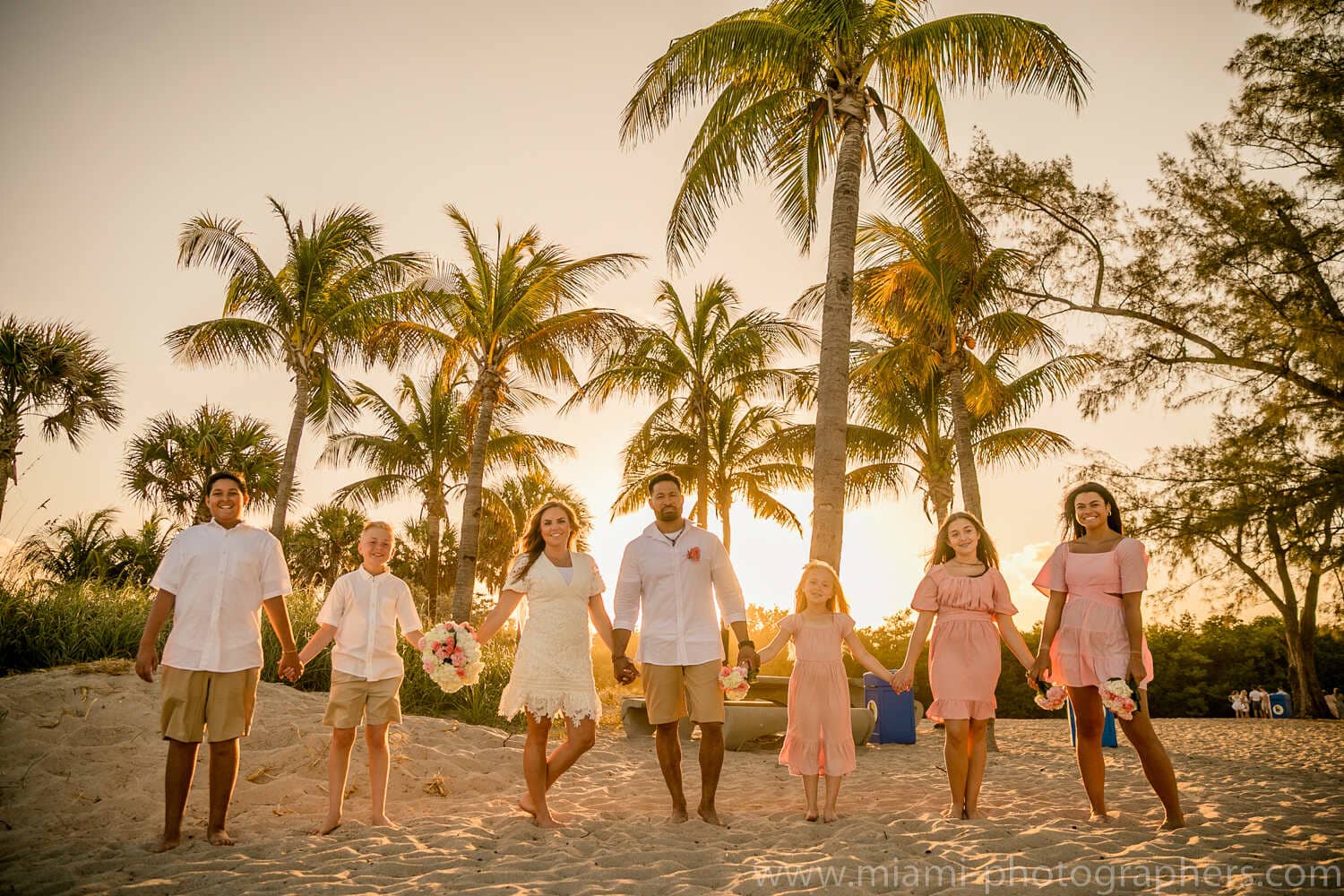 Bride and groom embracing at sunset during their intimate Miami beach wedding, with warm golden light and gentle ocean waves.