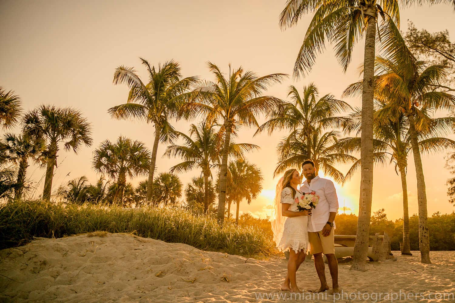 Bride and groom sharing a joyful moment on a Miami beach during their intimate wedding, with soft natural light and ocean waves in the background.