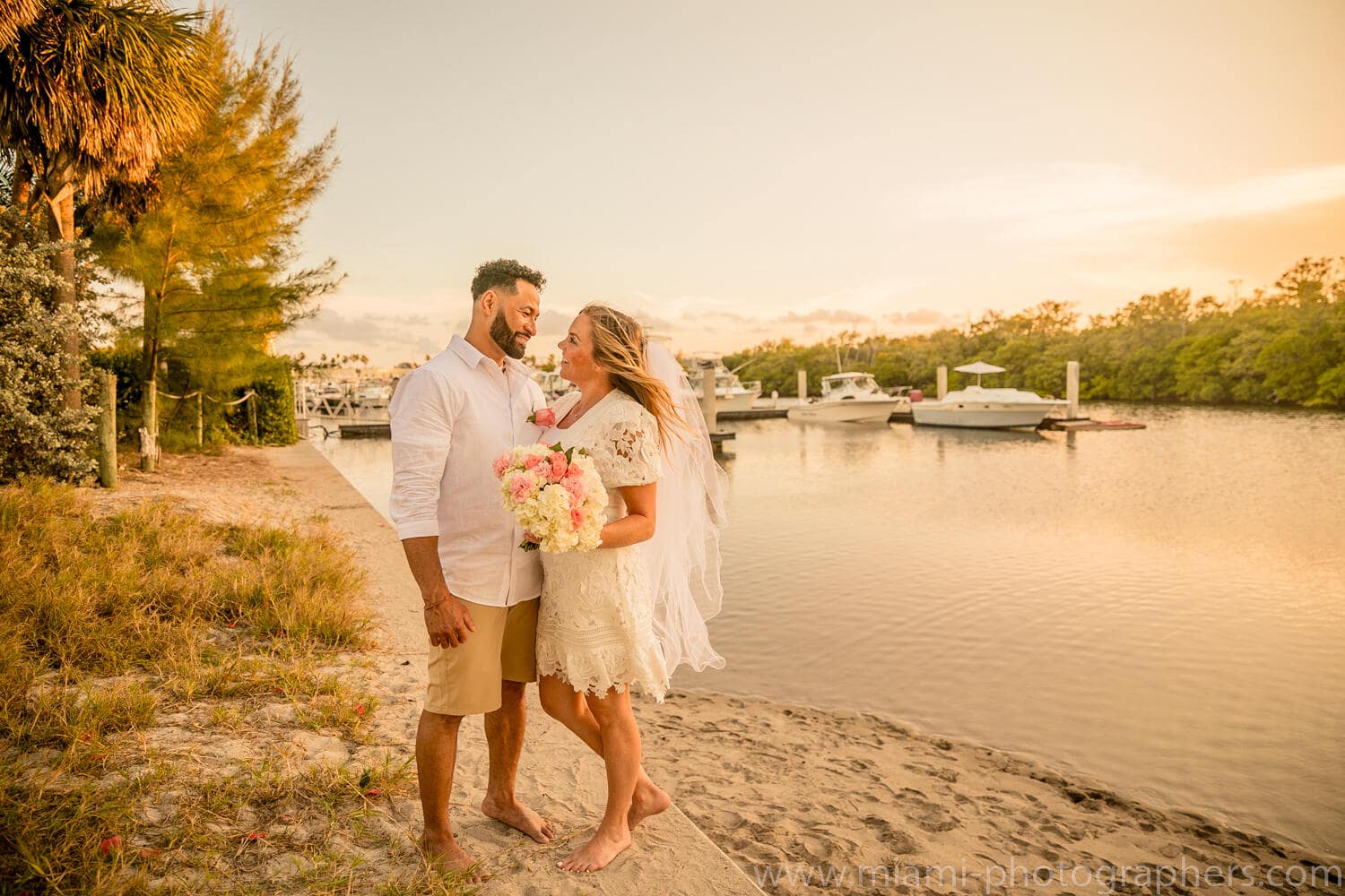 Bride and groom sharing a tender moment at sunset during their intimate Miami beach wedding, with soft golden light and ocean waves in the background.