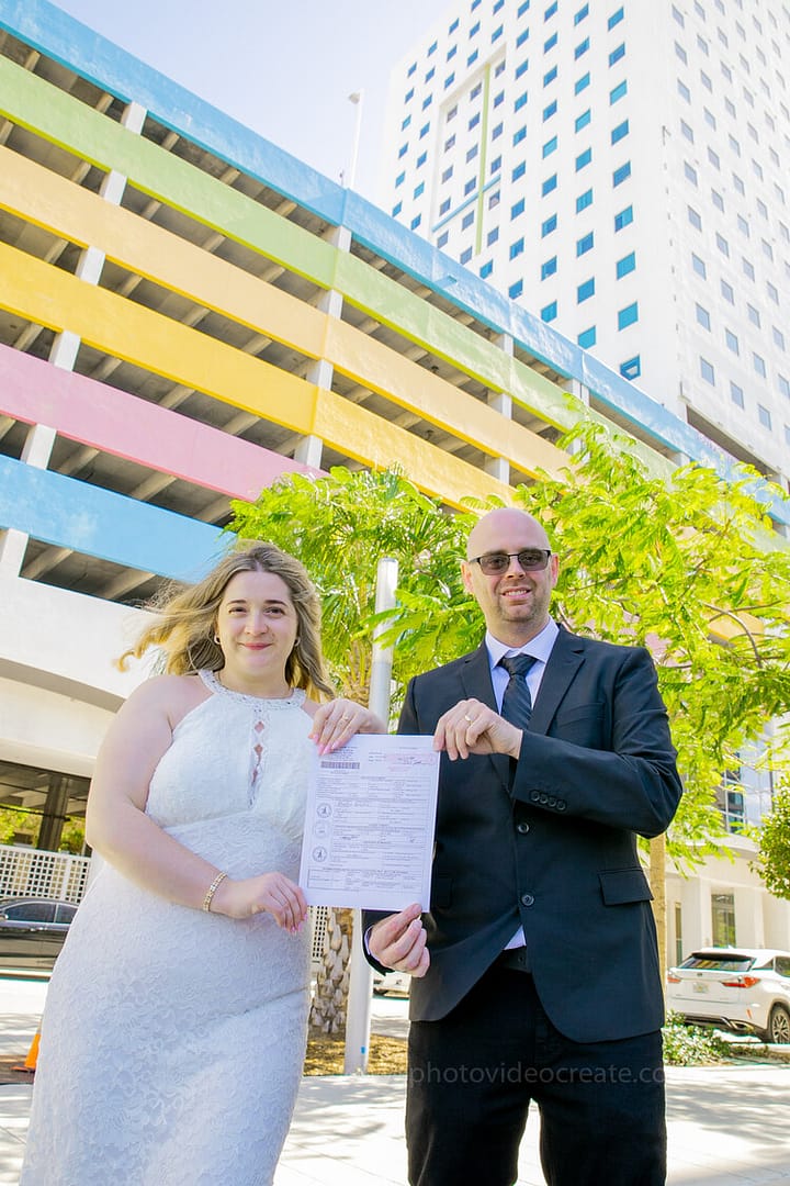 Bride and groom posing for a stylish wedding portrait in front of Miami Beach City Hall, capturing their special day