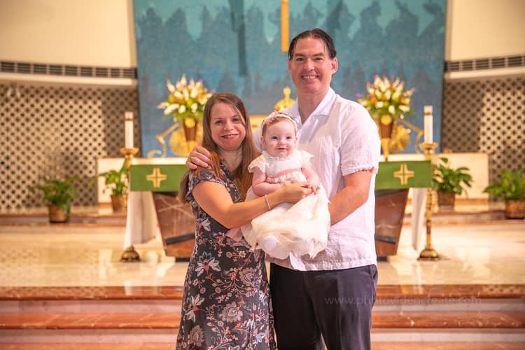 Close-up of baby in white baptism outfit before ceremony at St. Rose of Lima Church in Miami