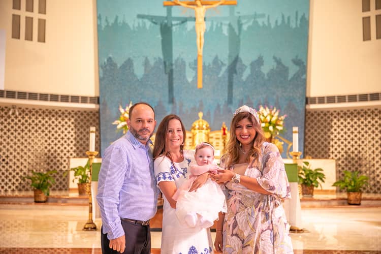 Baby being held by parents during baptism ceremony at St. Rose of Lima Church in Miami