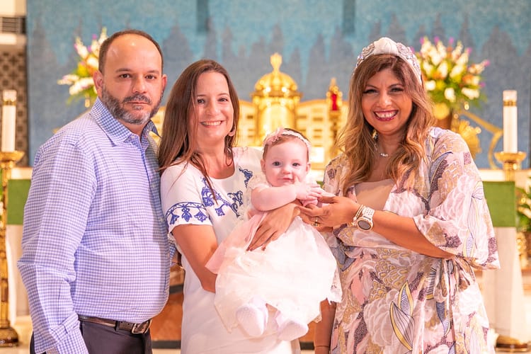 Family smiling together after baptism ceremony at St. Rose of Lima Church in Miami