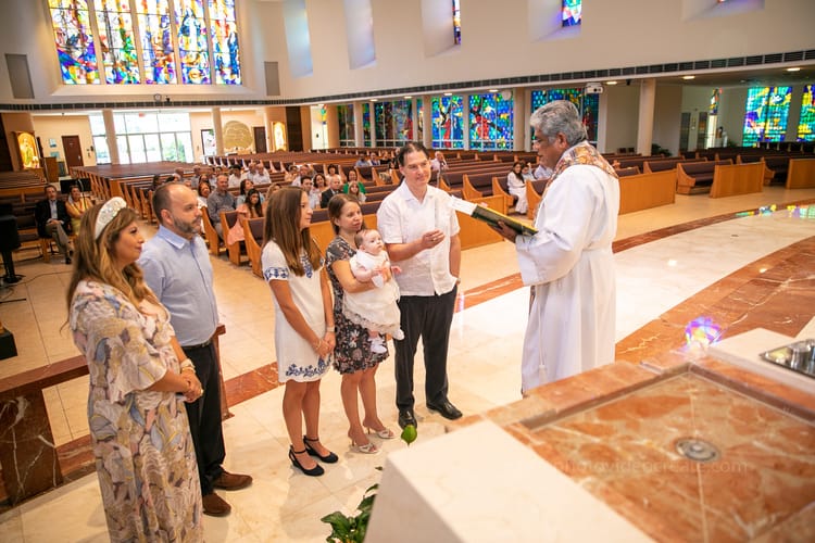 Godparents and parents standing by the baptismal font during ceremony