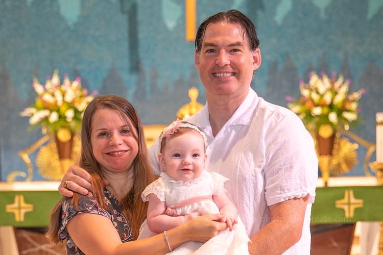 Catholic priest pouring holy water during baptism ceremony at St. Rose of Lima Church in Miami