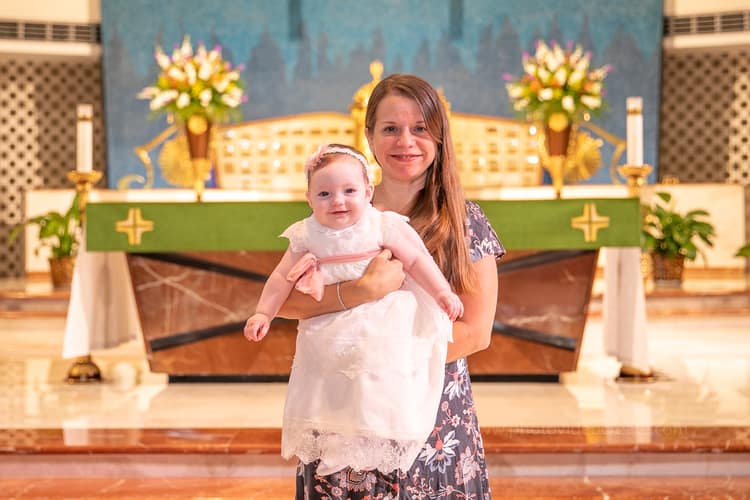 Godparents and parents standing by baptismal font during baptism ceremony at St. Rose of Lima Church in Miami