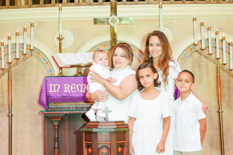 Mother holding baby during emotional baptism ceremony at Coral Gables United Church of Christ in Miami